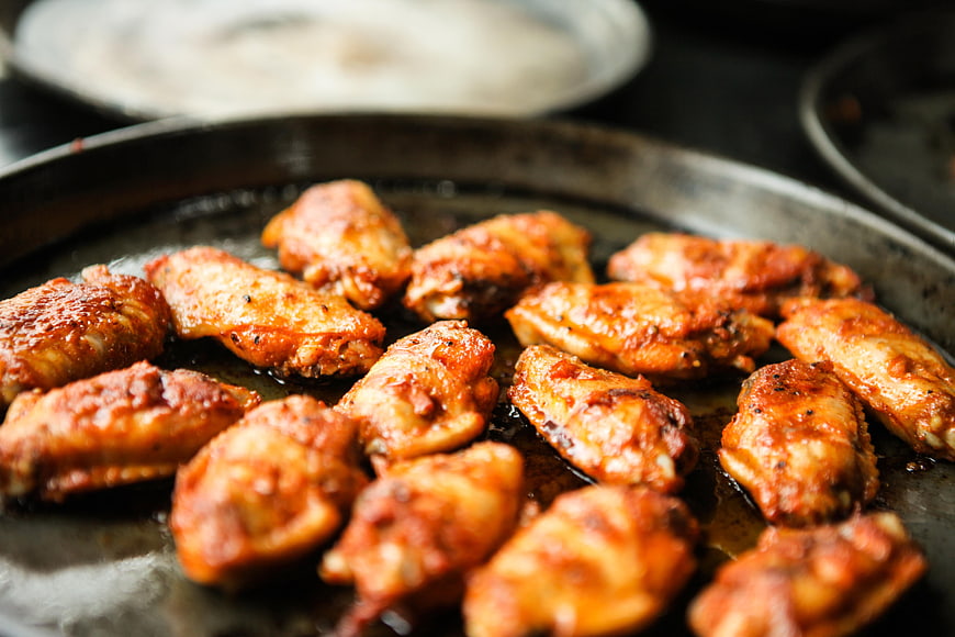 Glossy grilled chicken wings on a dark metal platter
