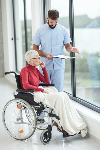 Male nurse consulting with elderly woman in wheelchair