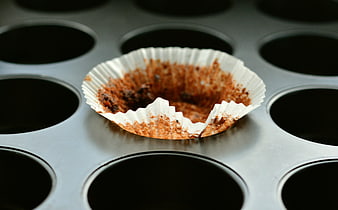 Empty chocolate muffin liner in metal baking pan