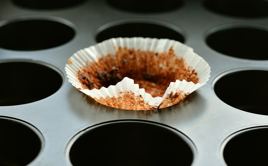 Empty chocolate muffin liner in metal baking pan