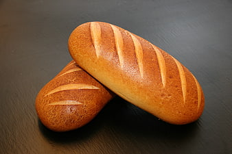 Two Golden Brown Loaves of Bread on Dark Slate