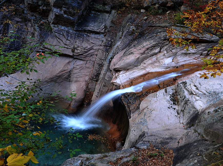 Small waterfall cascading over rocks in autumn forest