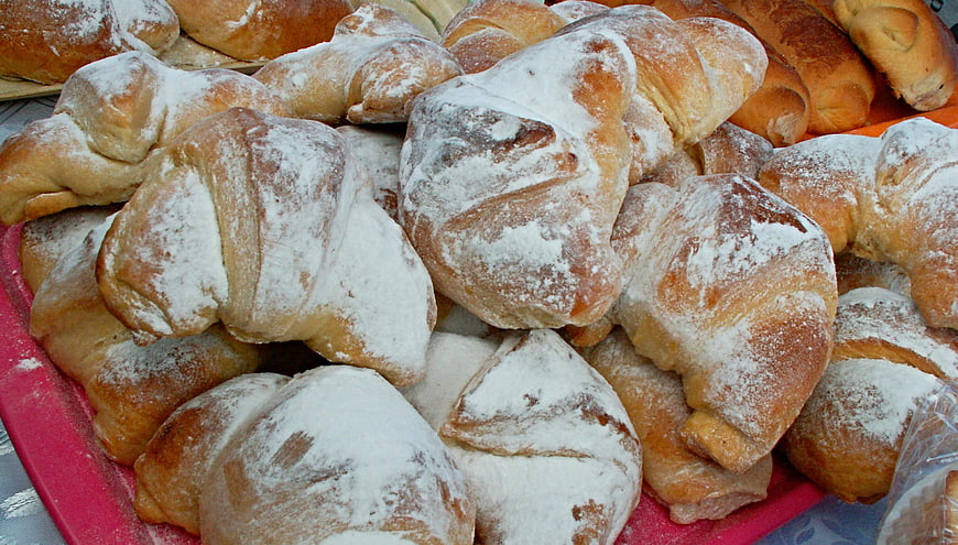 Freshly baked flour-dusted bread rolls in a bakery basket