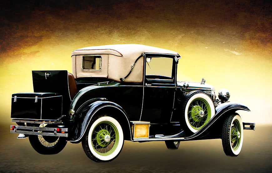 Vintage black antique car with green wheels and beige convertible top