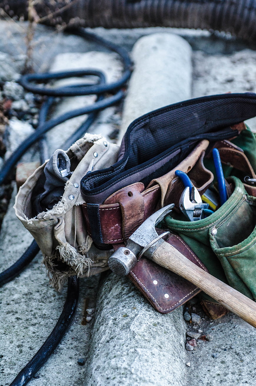 Worn Leather Tool Belt with Hammer and Wrench on Construction Site