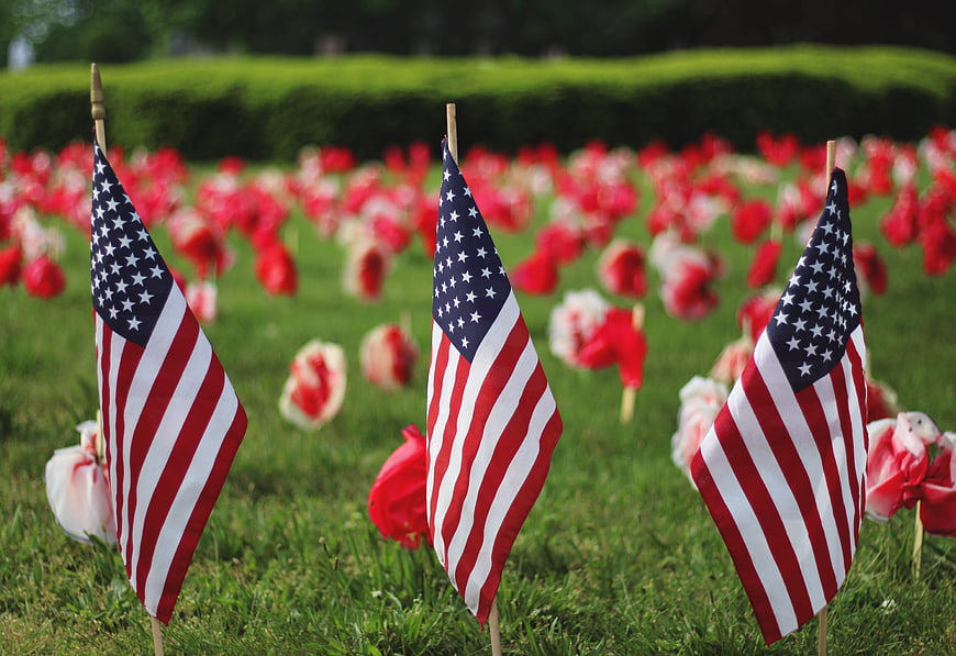 American flags and red poppies on a memorial day cemetery lawn