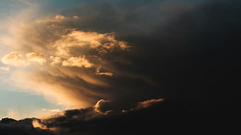 Dramatic sunset clouds with golden light rays breaking through dark stormy sky