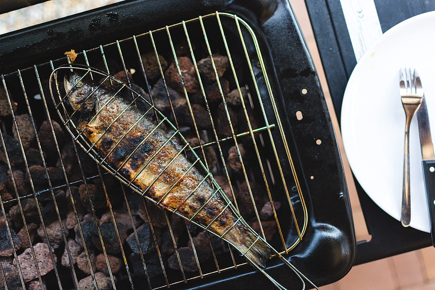Top View of Grilled Fish in Wire Basket on Charcoal Grill