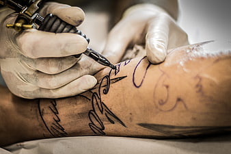Close-up of tattoo artist inking a design on a client's arm