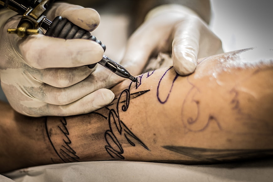 Close-up of tattoo artist inking a design on a client's arm