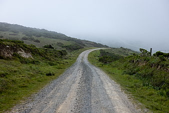 Winding gravel road through foggy green hills