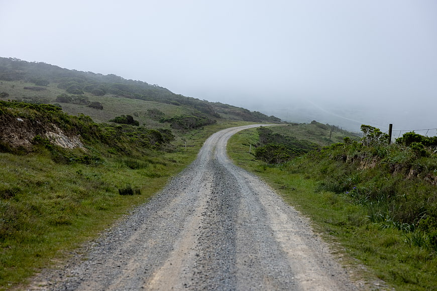 Winding gravel road through foggy green hills