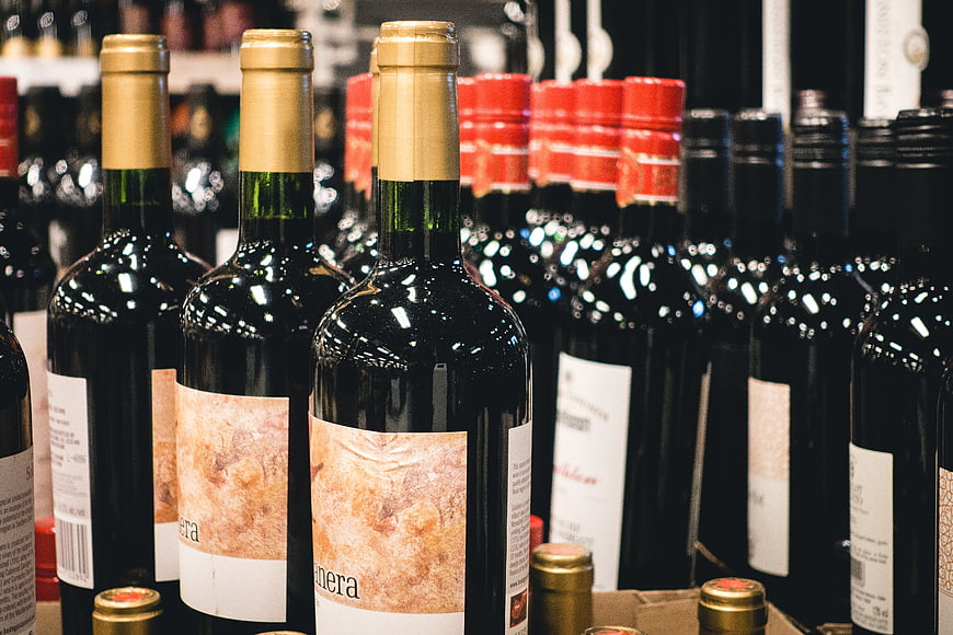 Rows of red wine bottles on store shelves
