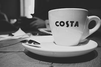 Black and white Costa coffee cup on wooden table