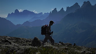 Hiker with backpack trekking on rocky mountain ridge