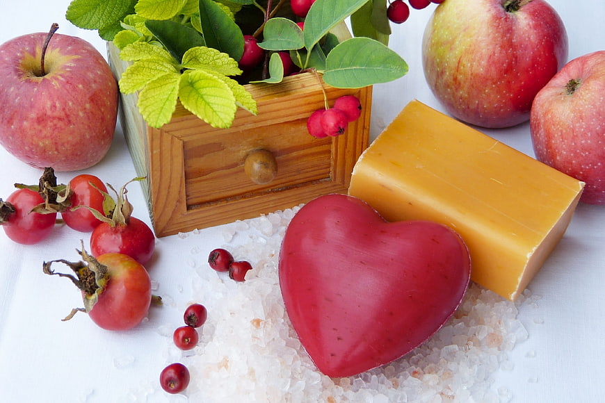 Heart-shaped red soap with apples and rose hips on salt