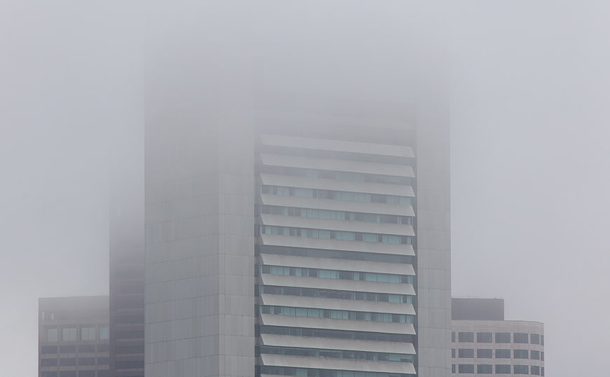 Modern skyscraper obscured by thick fog in city