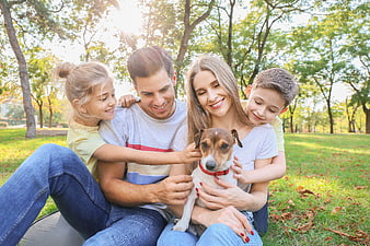 Happy family with dog sitting in park