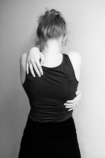 Black and white photo of woman hugging herself from behind