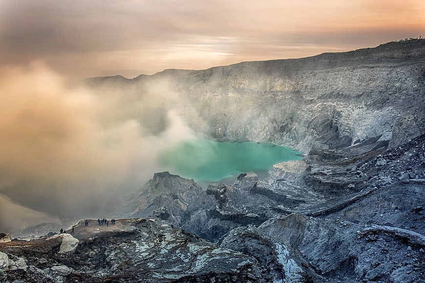 Dramatic volcanic crater with turquoise lake and smoke
