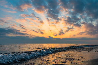 Dramatic Sunset Over Ocean Waves on Sandy Beach