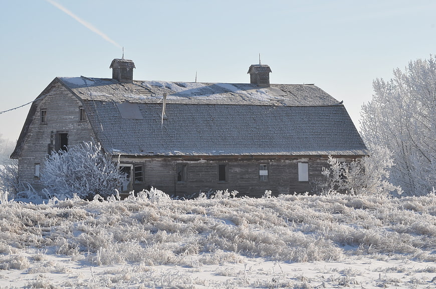 Old wooden barn covered in frost and snow in winter
