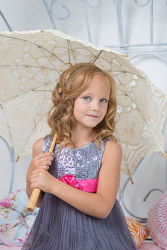 Portrait of a young girl in a sequined dress holding a lace parasol