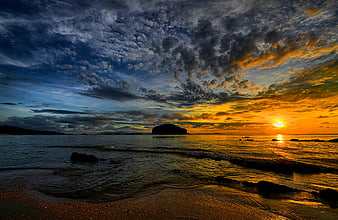 Dramatic Sunset Over Ocean with Rocky Island and Cloudy Sky