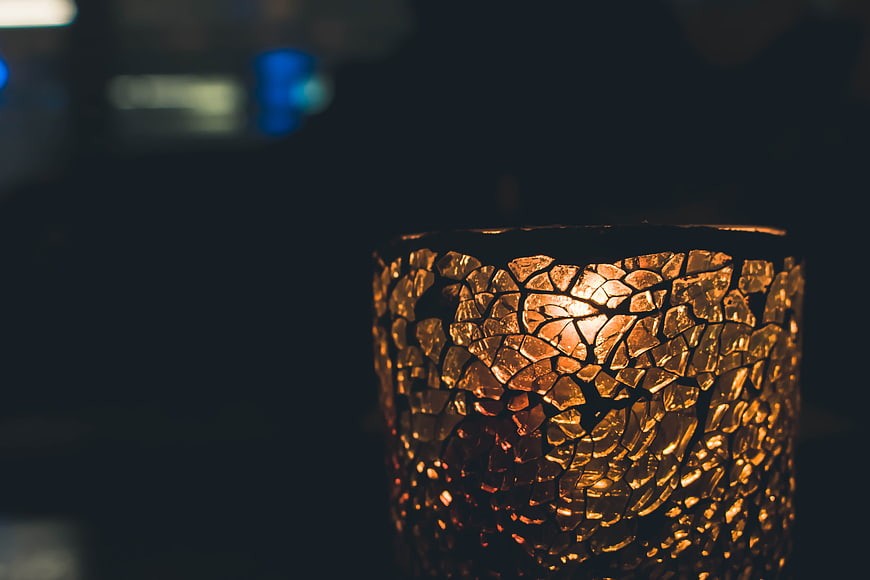 Close-up of textured amber glass candle holder in dark setting
