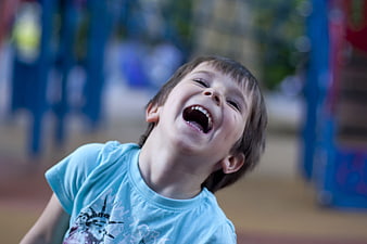 Laughing young boy in blue shirt at playground