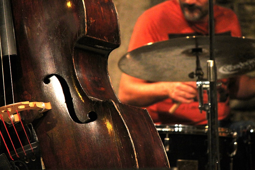 Close-up of double bass and drummer in red shirt during live jazz performance