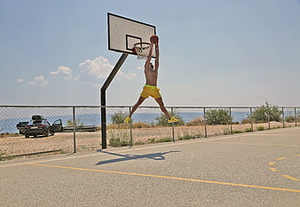 Male Athlete Dunking Basketball On Outdoor Court Near Beach