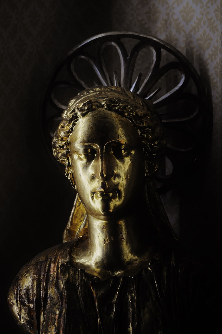 Golden religious statue bust with dramatic lighting
