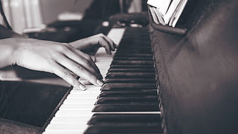 Close-up of hands playing piano keys in black and white