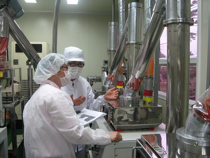 Workers in protective gear inspecting industrial food processing machinery