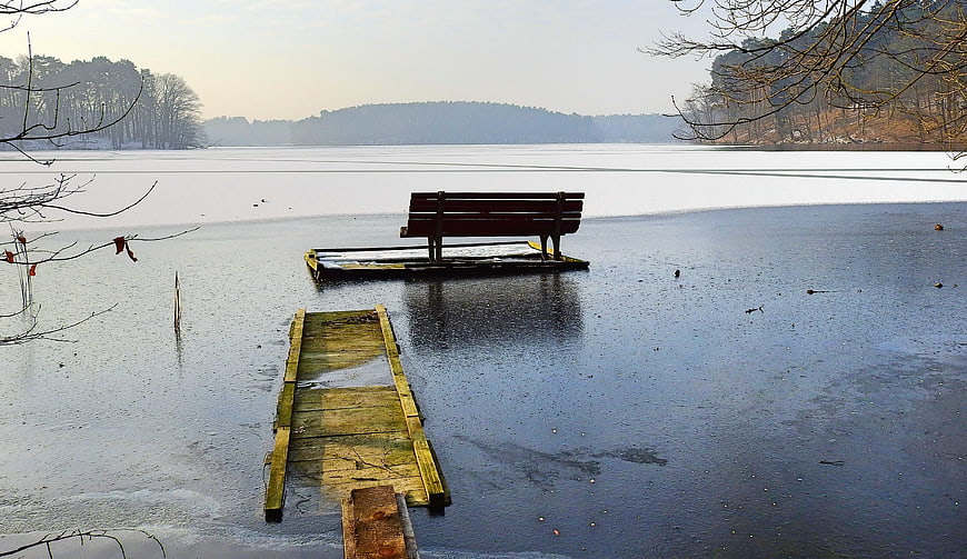 Lone wooden bench on frozen lake in winter landscape