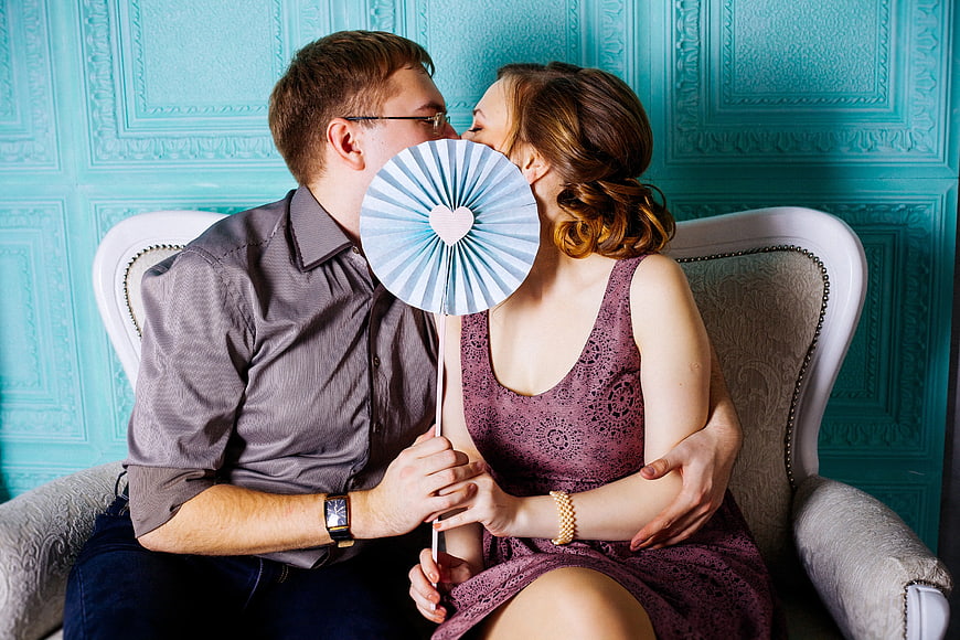 Couple Holding Photo Booth Fan on Loveseat