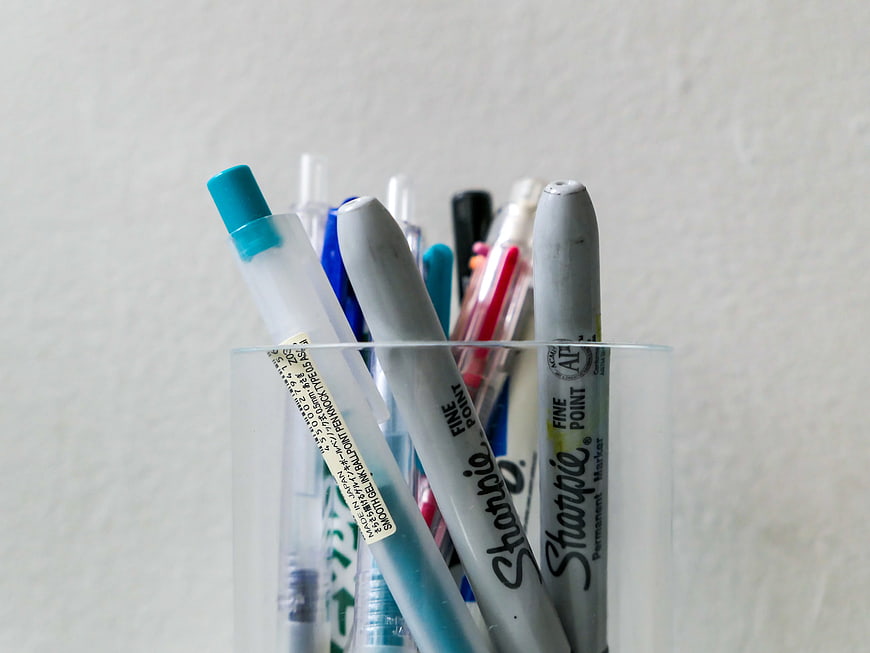 Assorted Pens and Markers in Clear Glass Cup