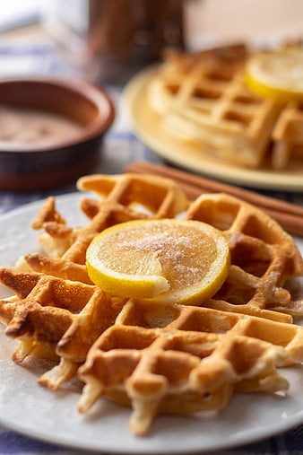 Close-up of golden waffles with lemon slice and cinnamon
