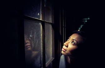 Woman looking out window at night with reflection