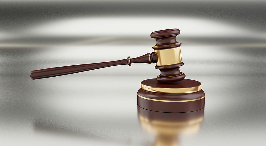 Wooden judge gavel with gold accents on a blurred gray background