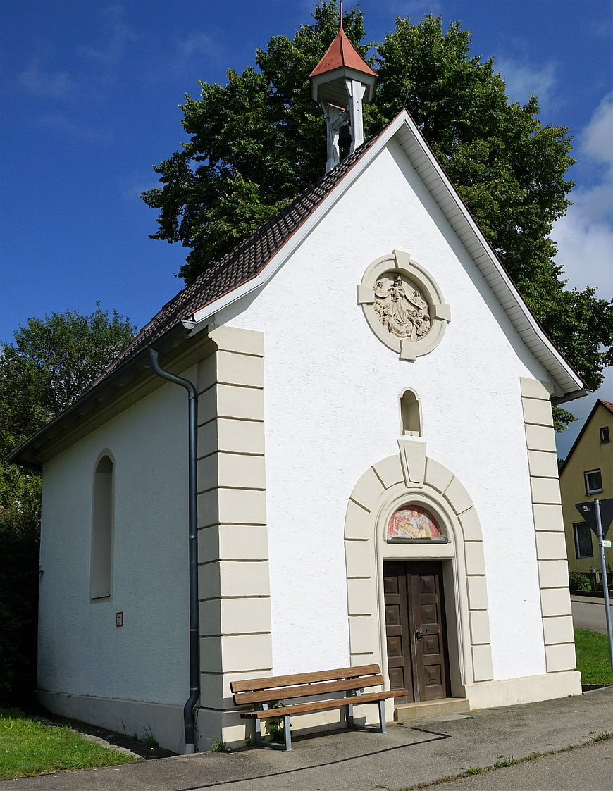 White Wayside Chapel with Wooden Bench in Summer