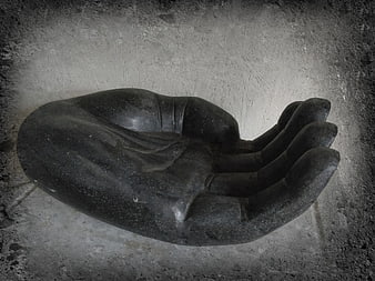 Black stone hand sculpture on textured concrete wall