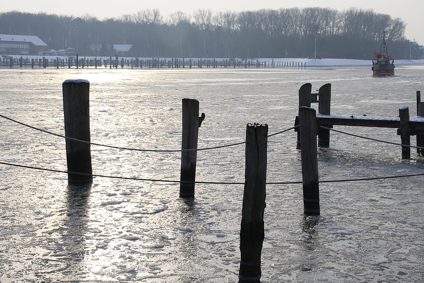 Frozen River with Wooden Pilings and Icebreaker Boat