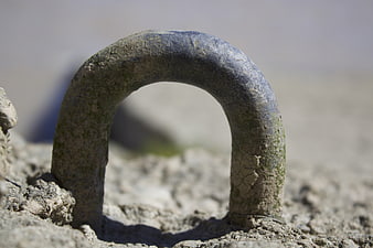Close-up of weathered metal mooring ring on concrete dock
