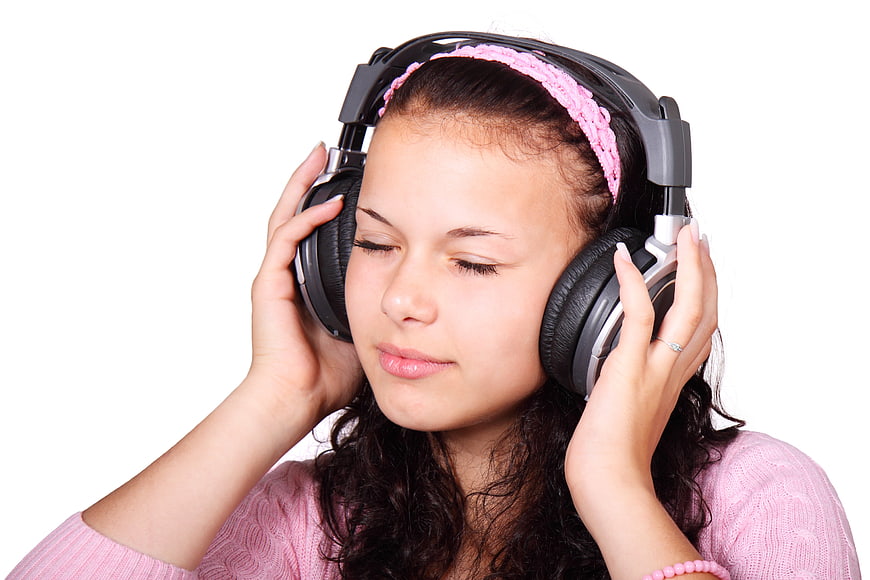 Young woman listening to music with headphones on white background