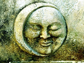 Close-up of weathered stone moon face sculpture with closed eyes