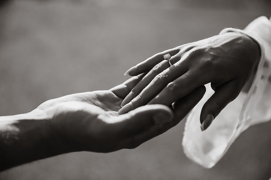 Black and white close-up of hands with engagement ring