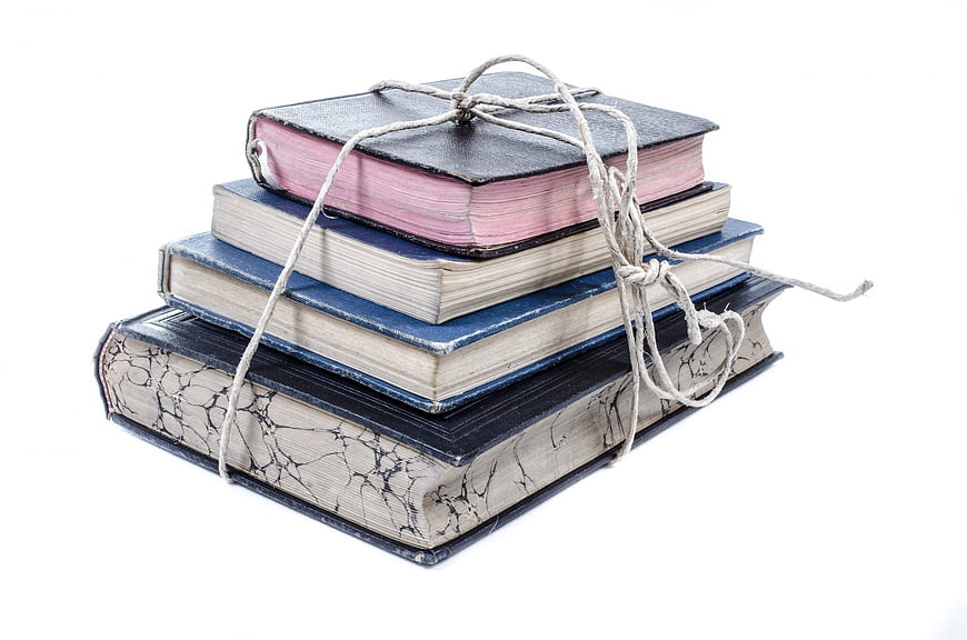 Stack of vintage books tied with twine on white background