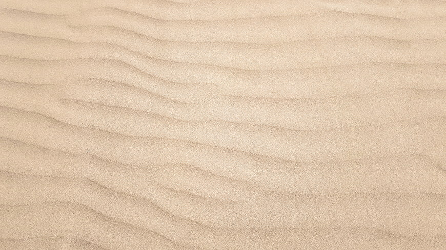 Close-up texture of rippled beige sand dunes